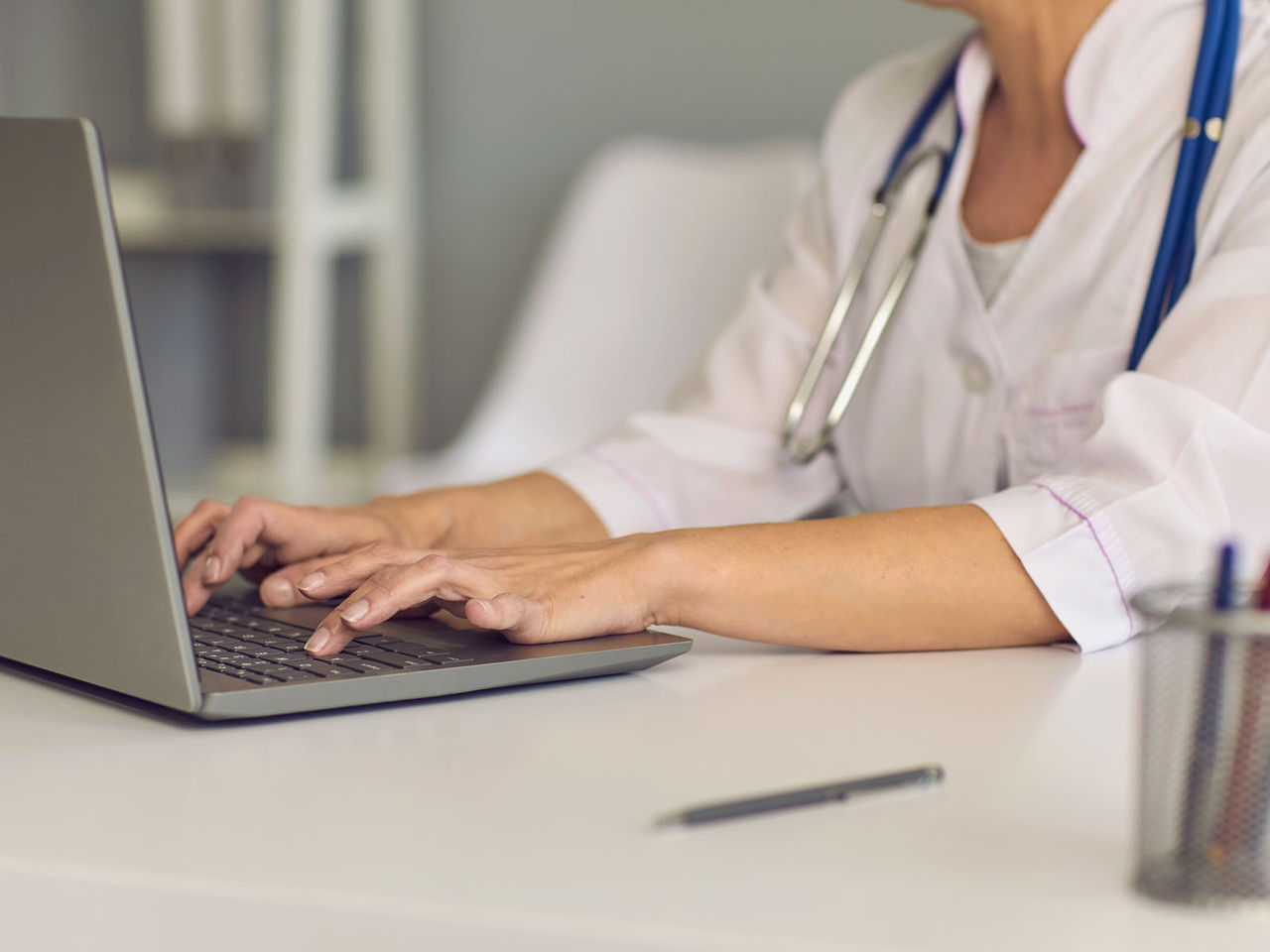 Profesional del cuidado de la salud escribiendo en un computador portátil.​​ 