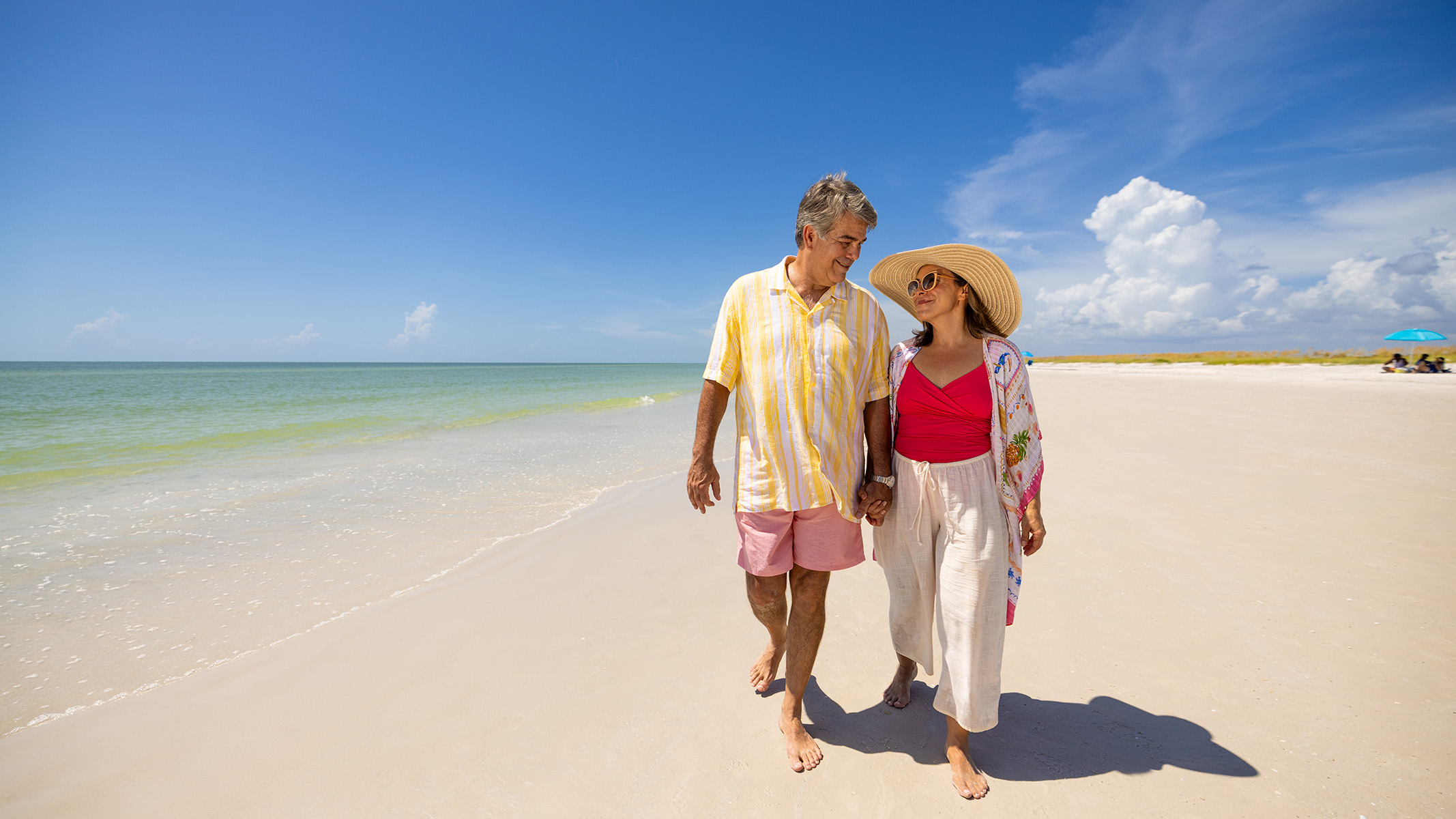 Pareja de personas mayores disfrutando de un paseo por la playa.​​ 