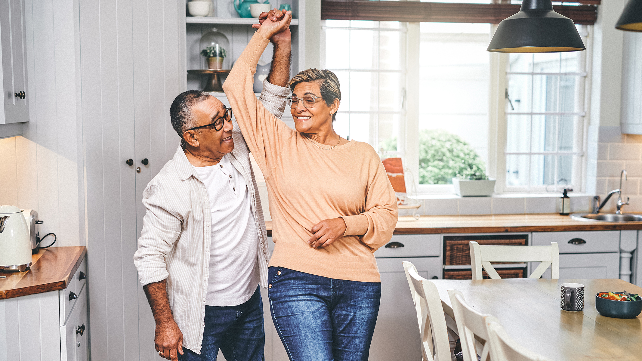  Pareja de personas mayores bailando en la cocina.​​ 