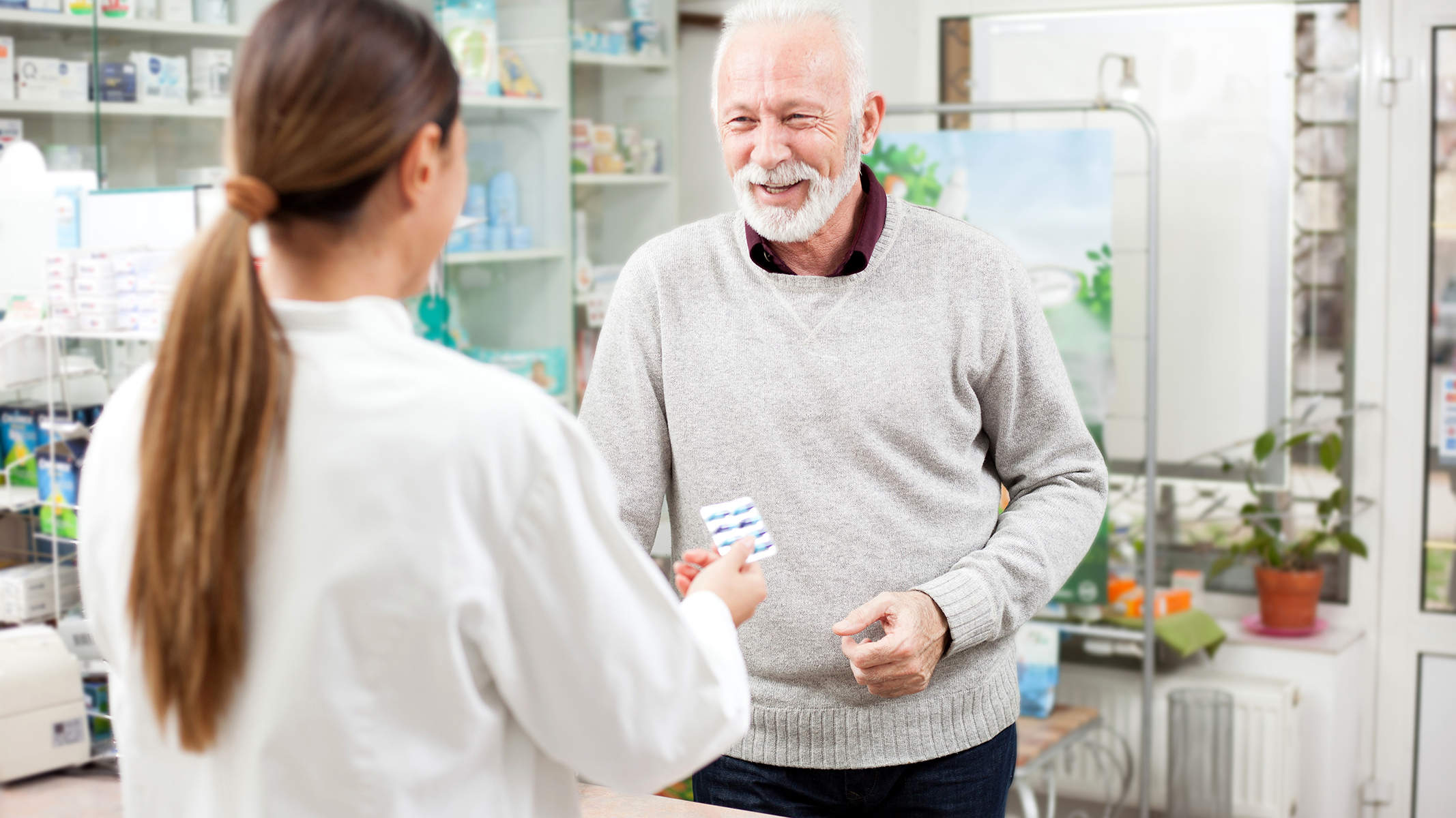 Hombre mayor comprando medicamentos en una farmacia.​​ 