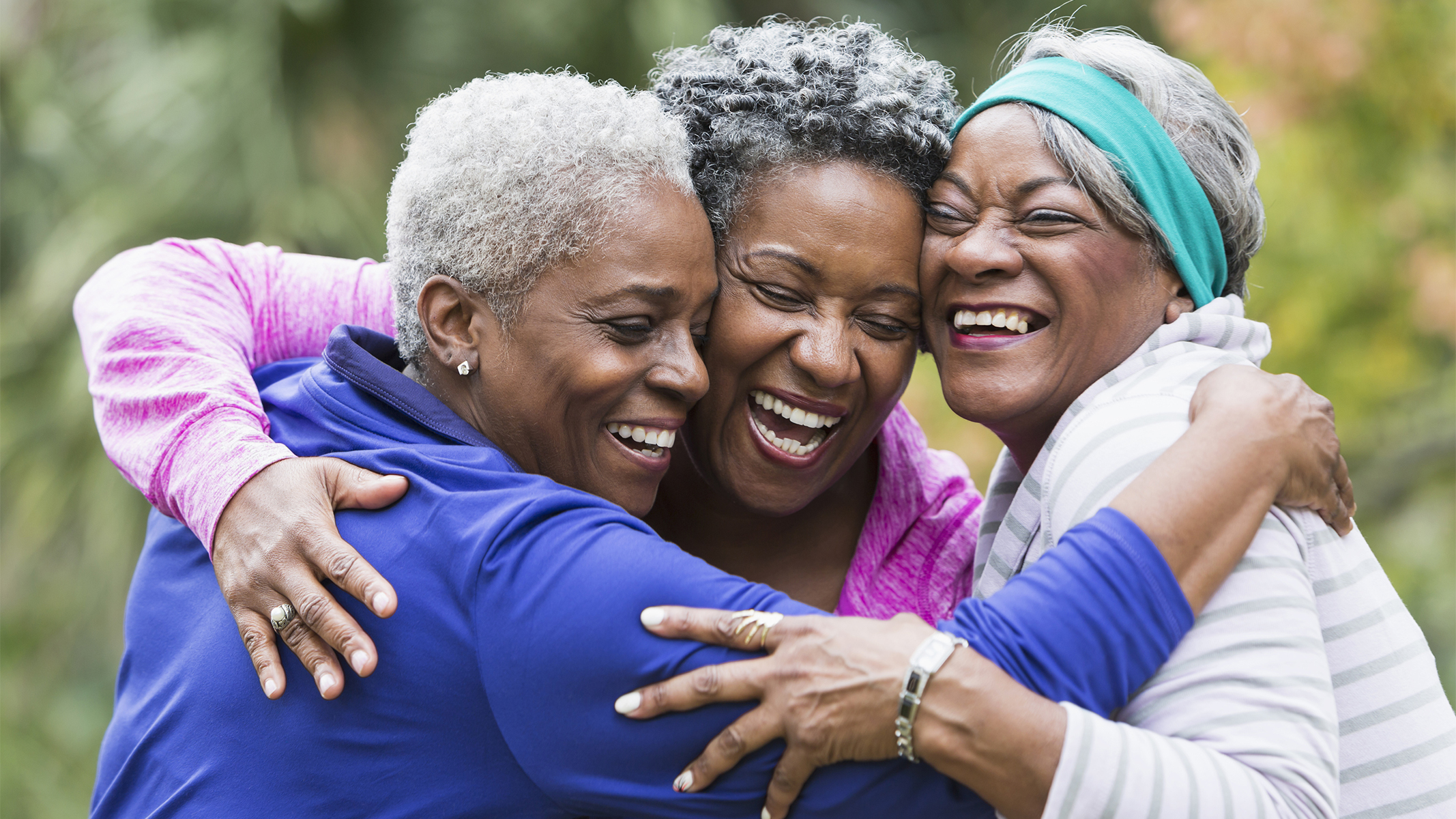 Tres mujeres mayores abrazándose.​​ 