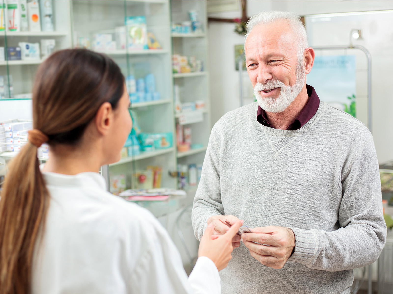 Hombre adulto en una farmacia pagando por su medicamento.​​ 