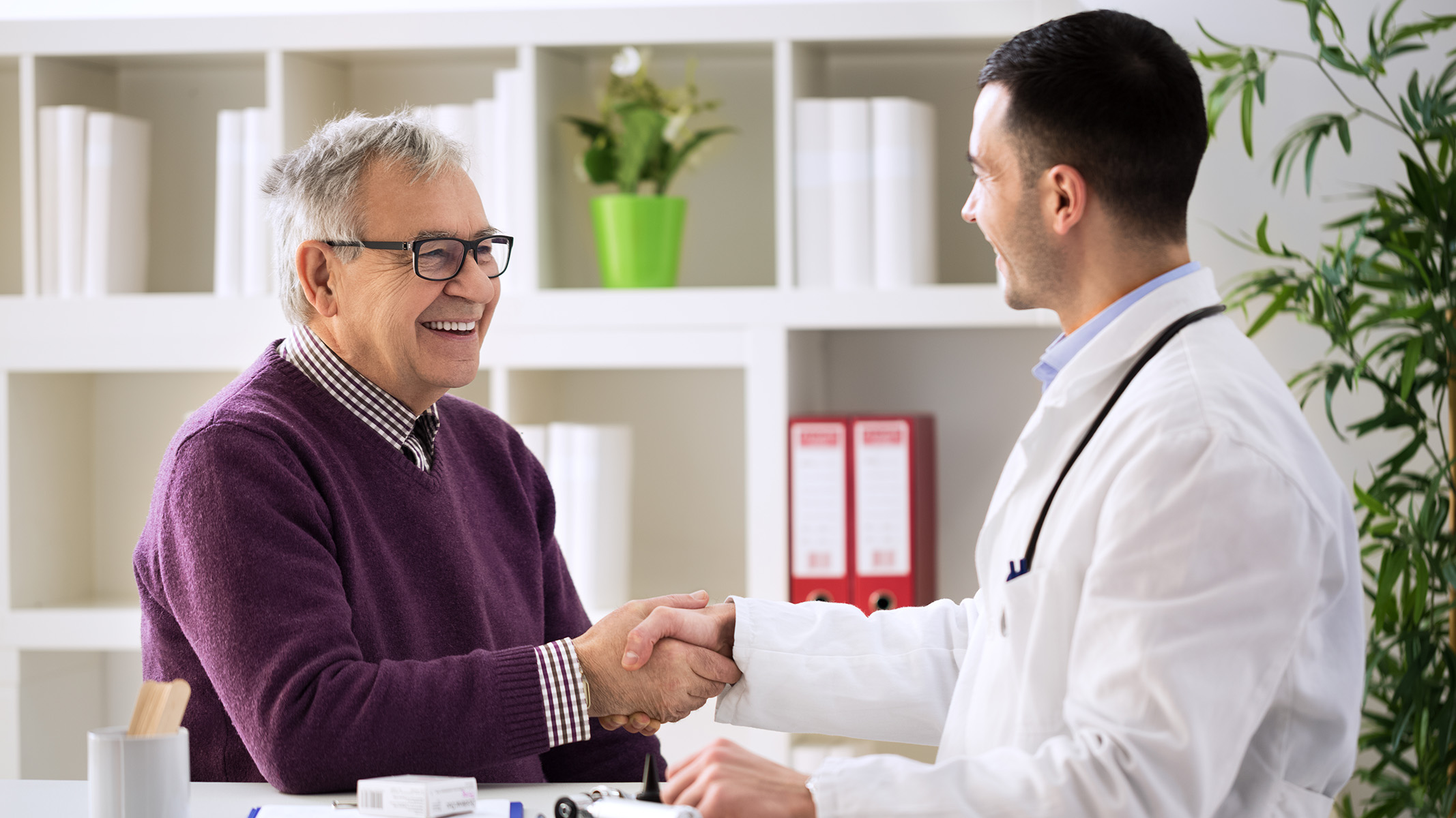  Hombre adulto saludando a un médico en un consultorio.​​ 