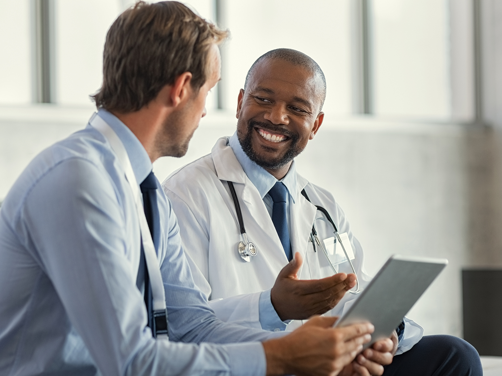 Dos médicos hablan y miran una tablet digital.​​ 