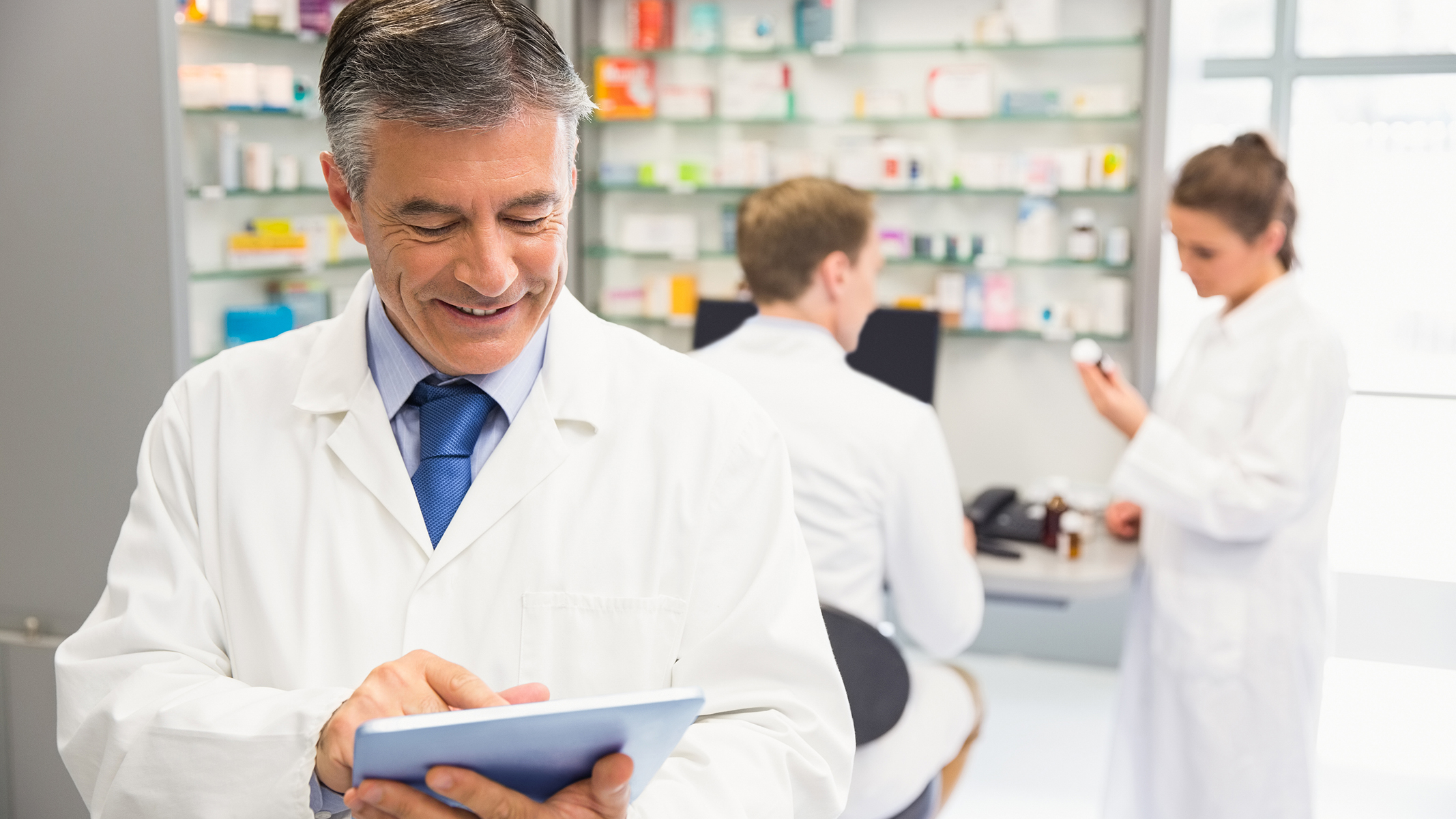 Farmacéutico utilizando una tablet en una farmacia.​​ 