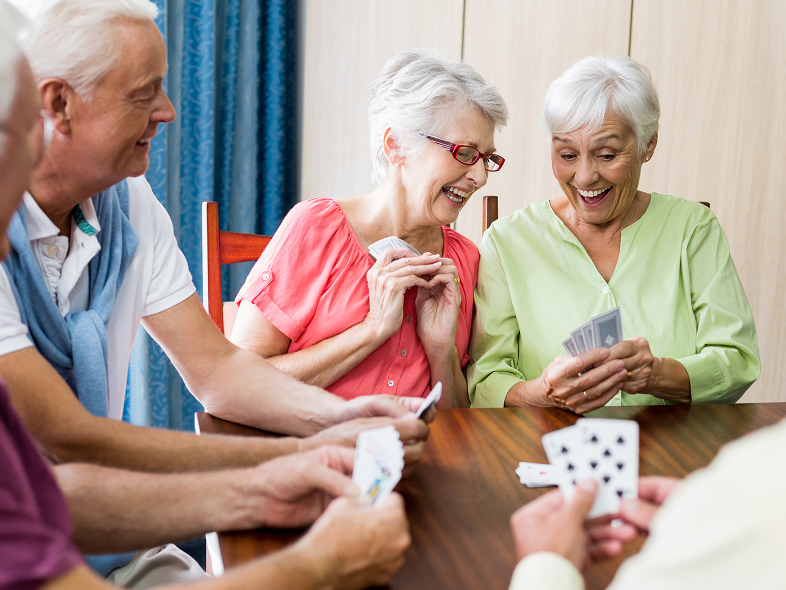 Grupo de personas mayores alrededor de una mesa jugando a las cartas​​ 