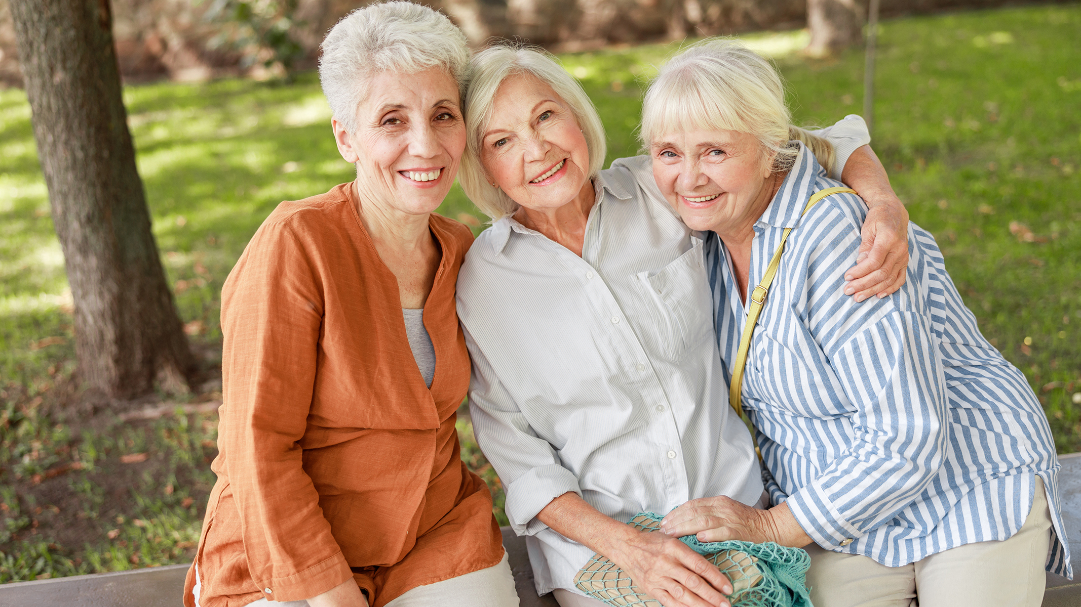  Grupo de  mujeres mayores sonriendo en un banco de la plaza​​ 