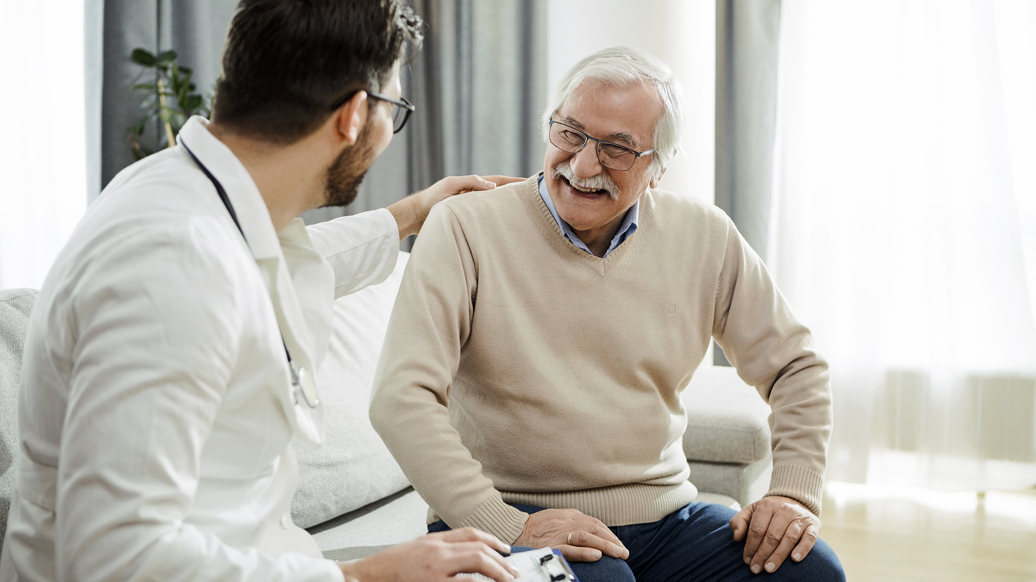 Hombre mayor sonriendo con un médico​​ 