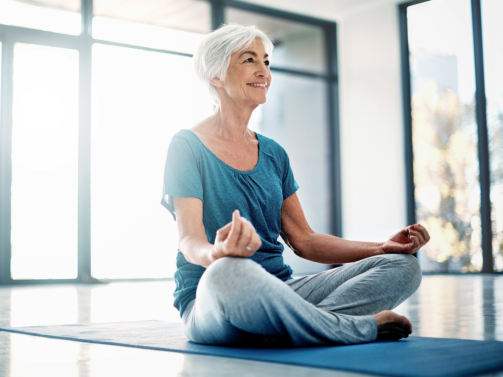 mujer mayor haciendo yoga en interiores​​ 