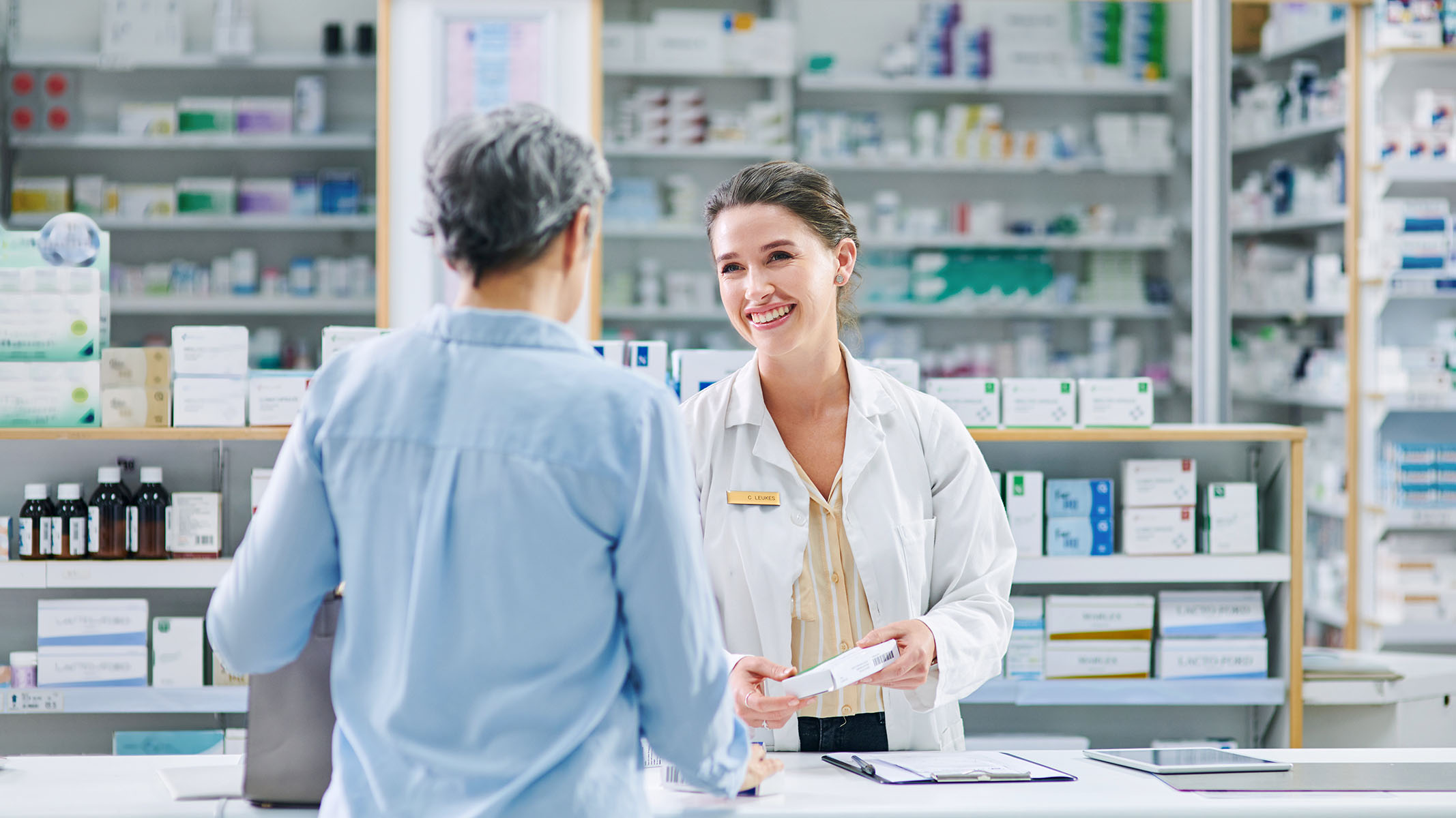 Farmacéutico ayudando a una mujer mayor en un mostrador de ventas​​ 