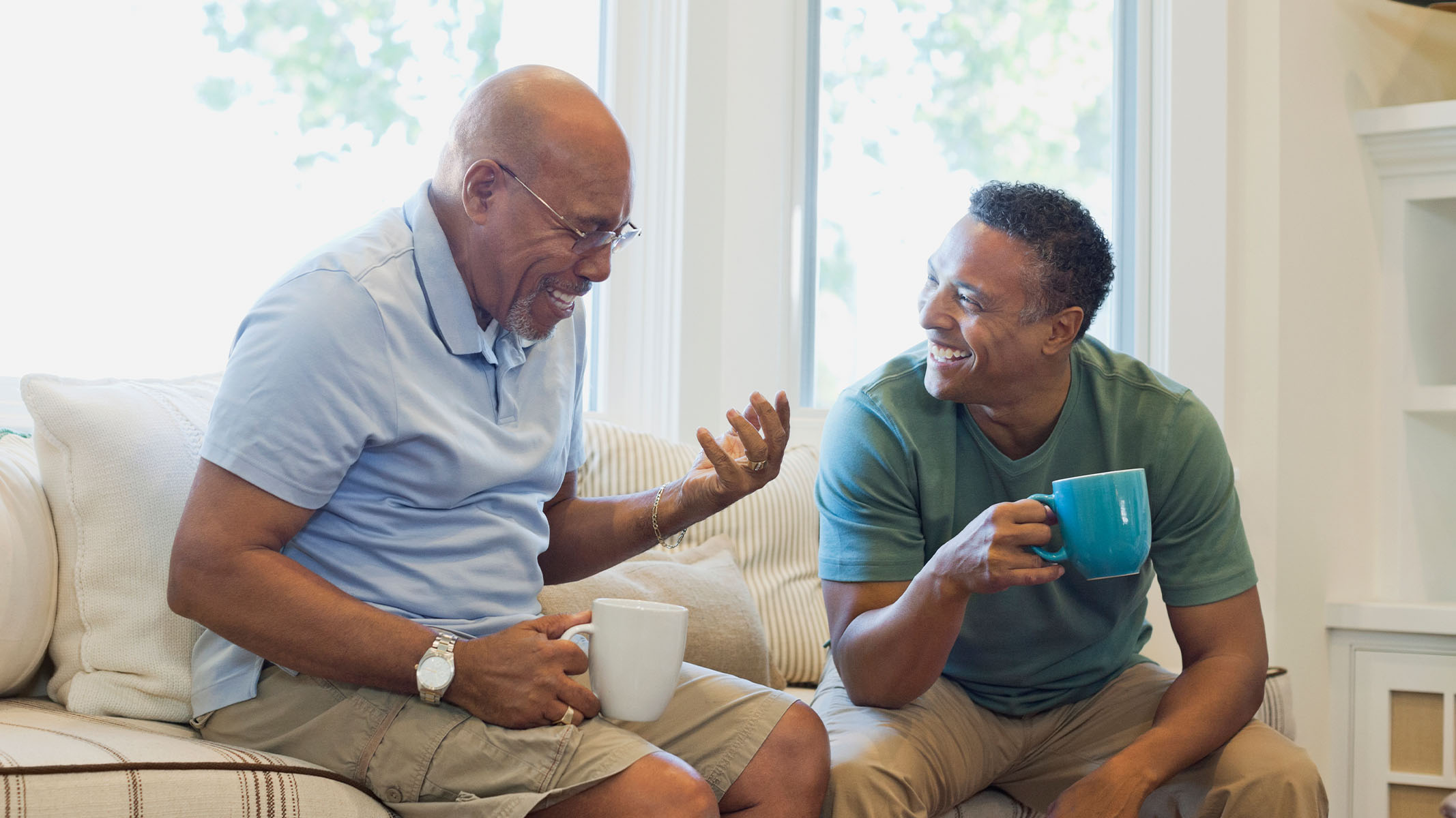 Un hombre mayor tomando un café con su hijo adulto.​​   