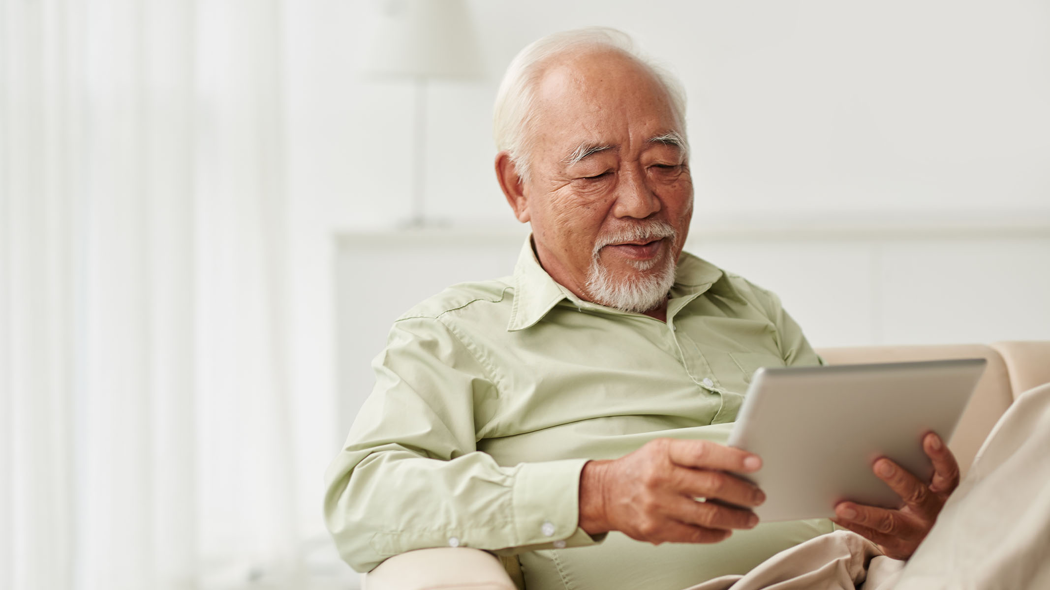 Un hombre mayor usando una tablet​​ 