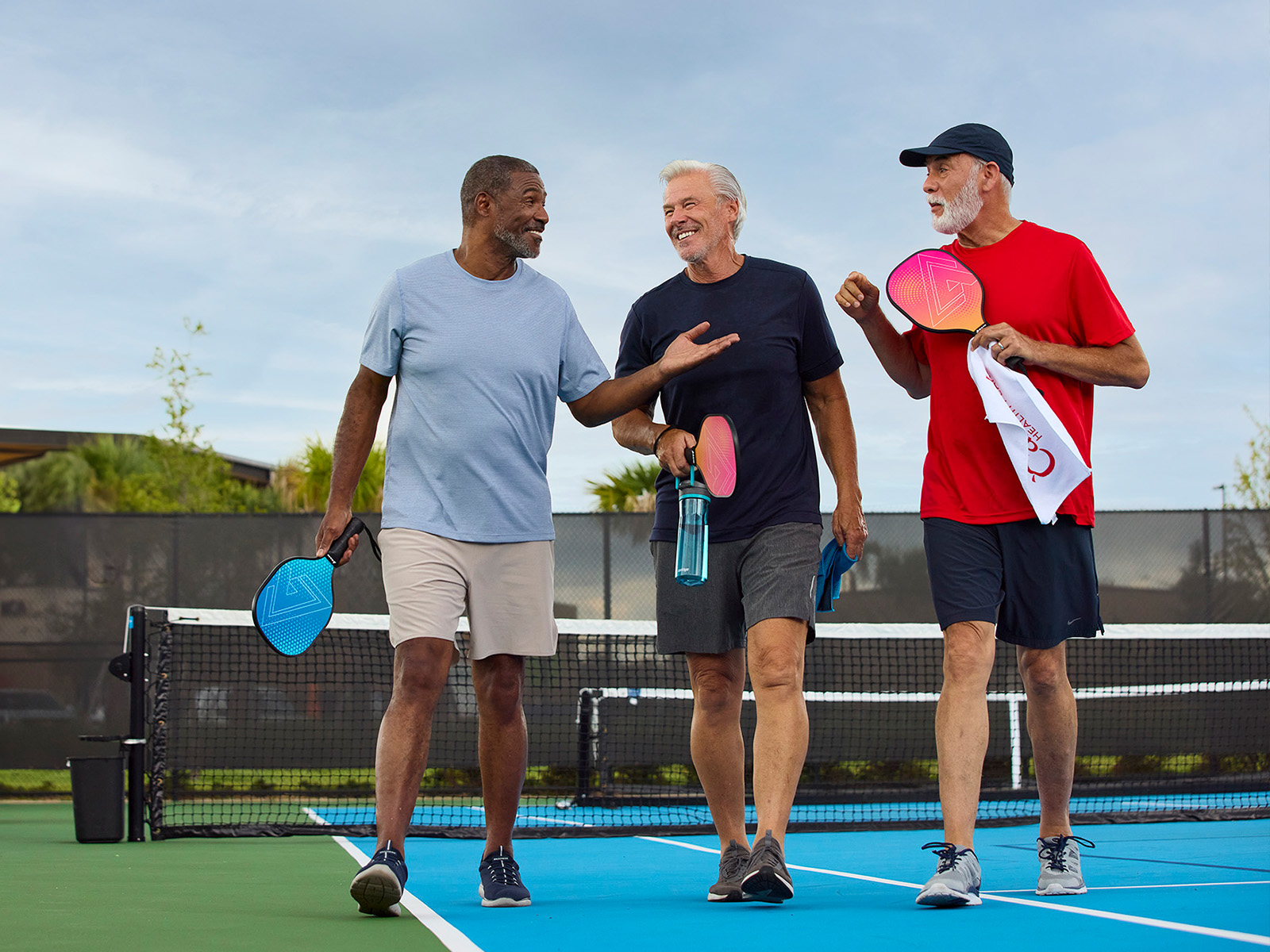Grupo de jugadores de pickleball de la tercera edad hablando después de un partido.​​ 