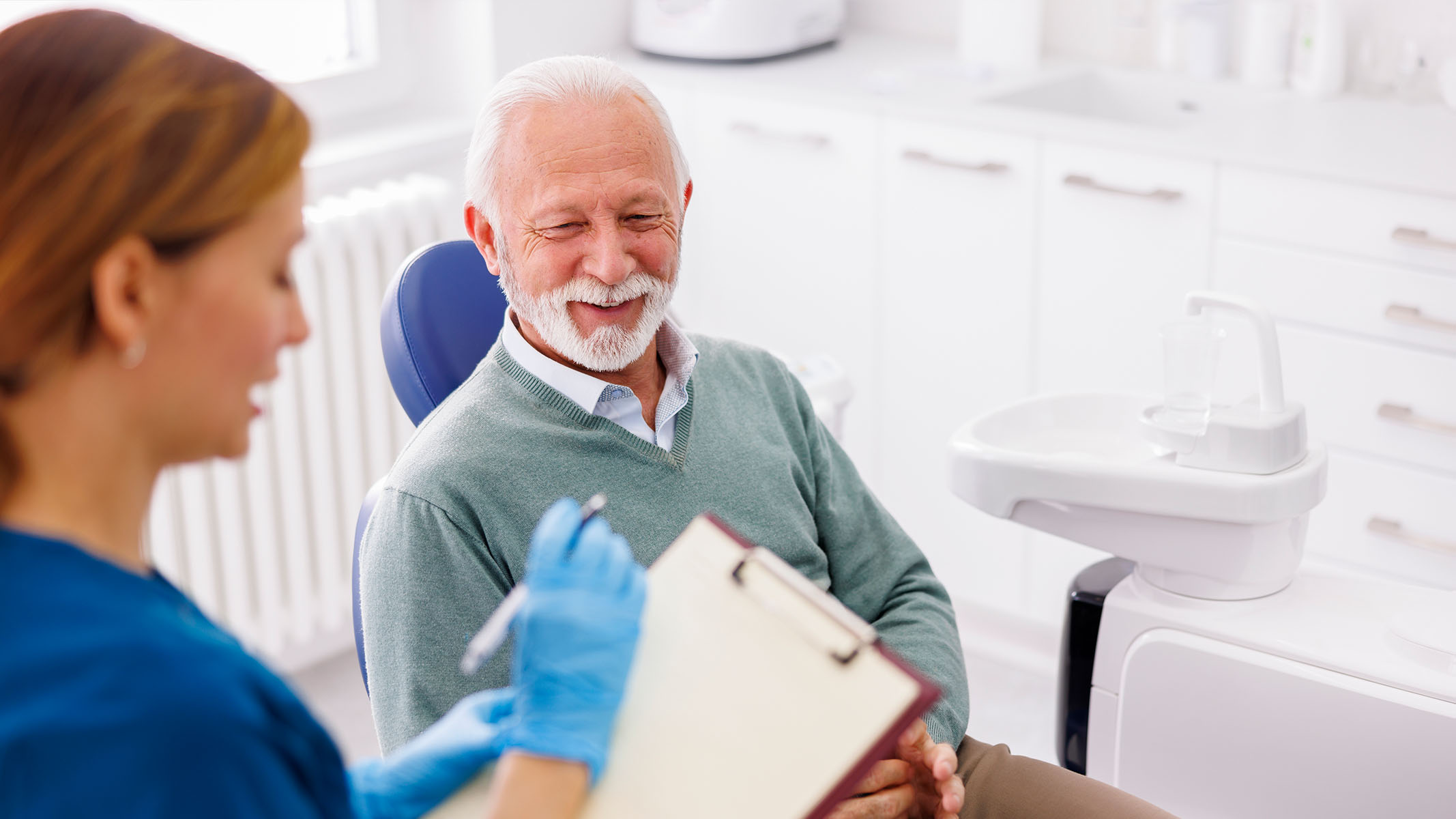 Una dentista le realiza un examen bucal de rutina a su paciente de la tercera edad.​​ 