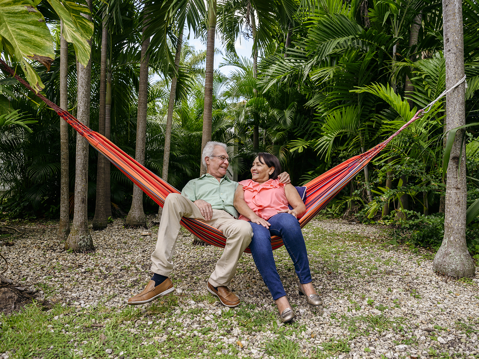 Pareja de personas mayores relajándose en una hamaca en el jardín​​ 