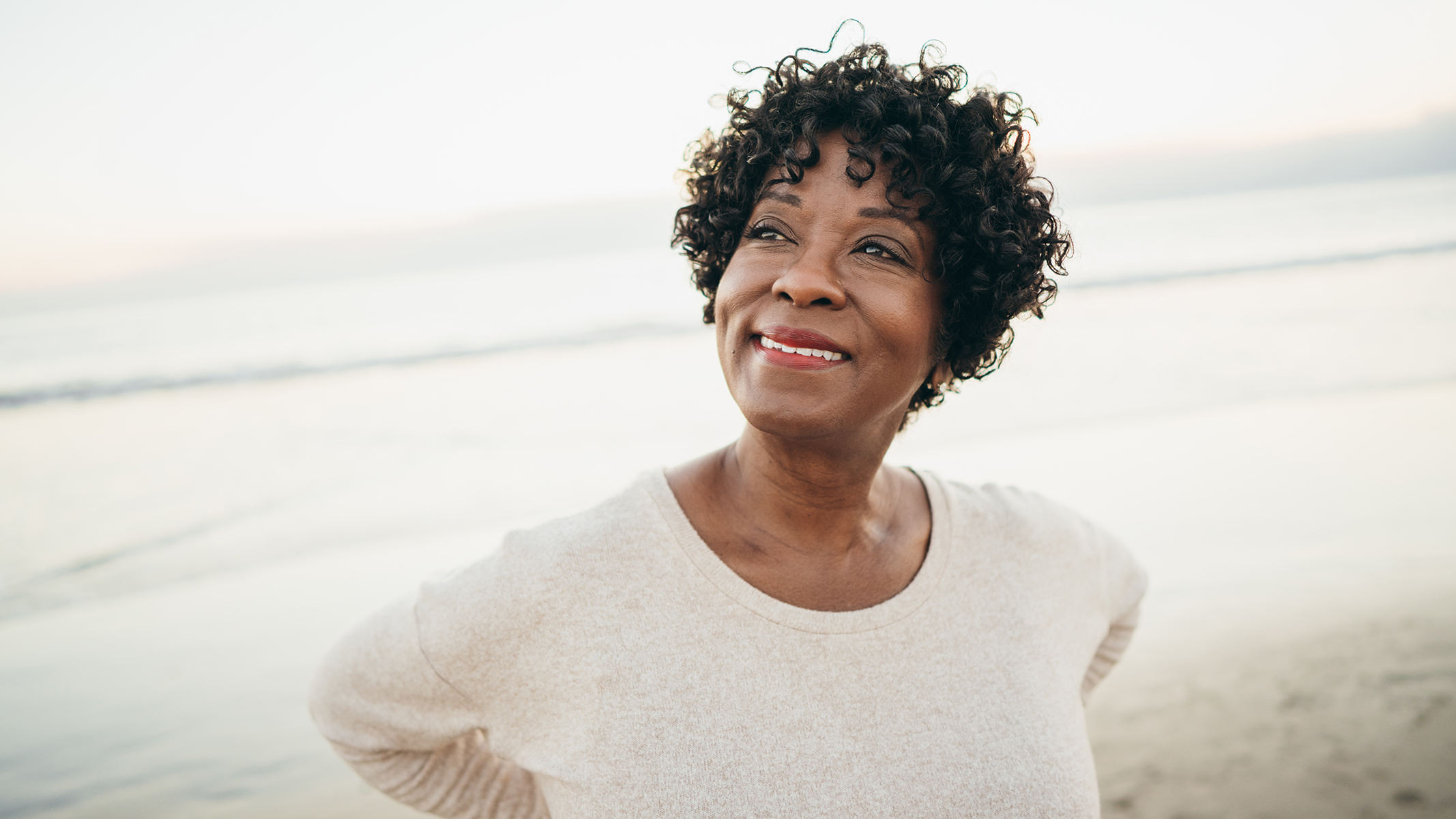 Mujer sonriendo en la playa.​​ 