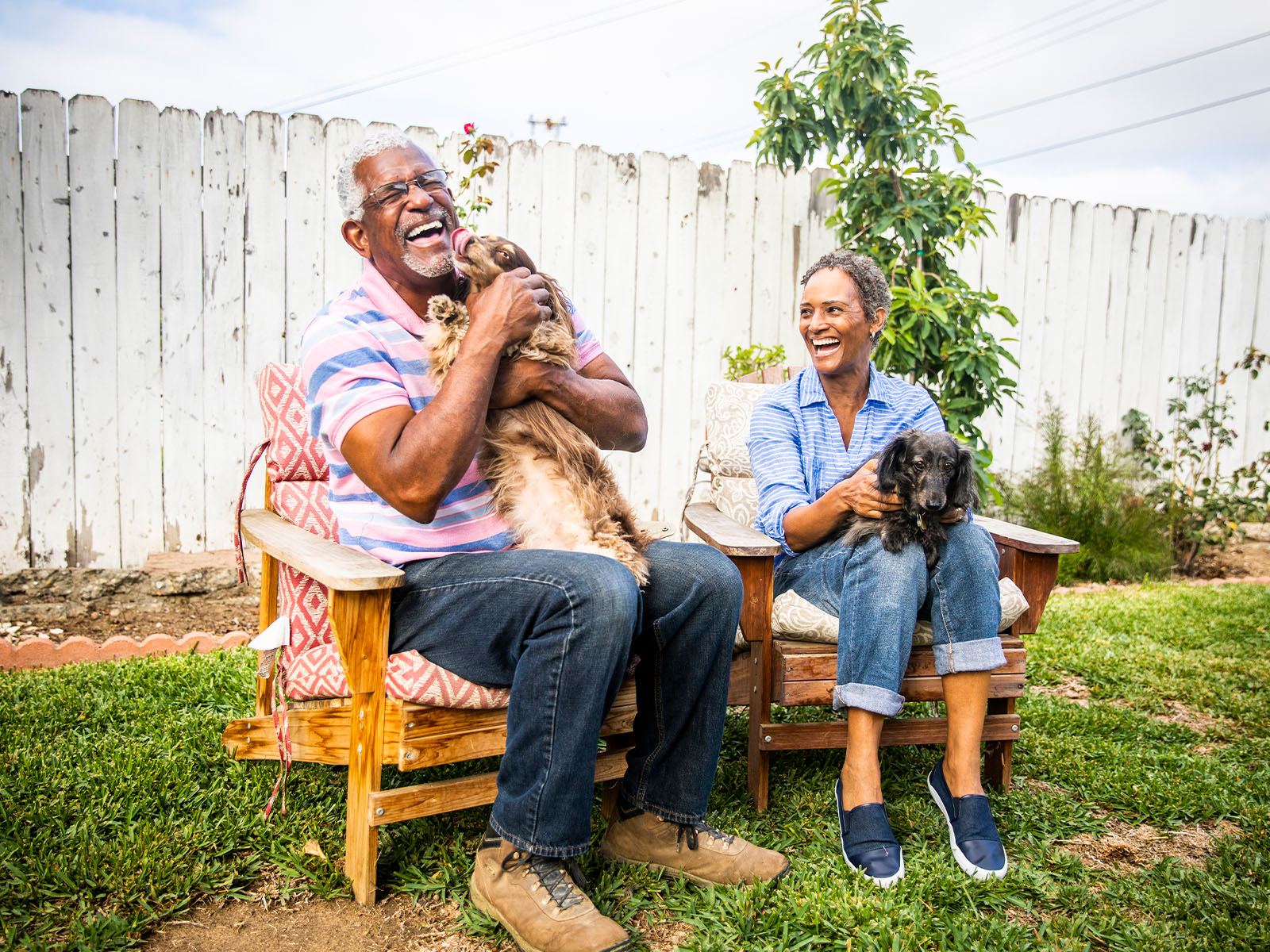  Una pareja de personas mayores jugando al aire libre con sus perros.​​ 