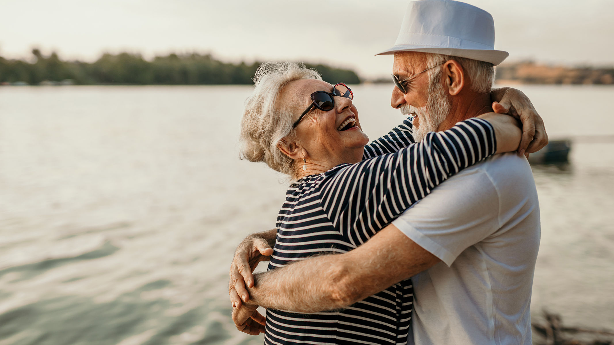 Pareja de personas mayores bailando en la playa.​​ 