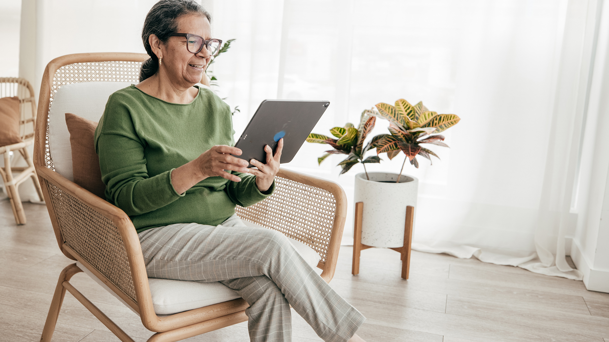  Mujer mayor sentada mirando una tablet.​​ 